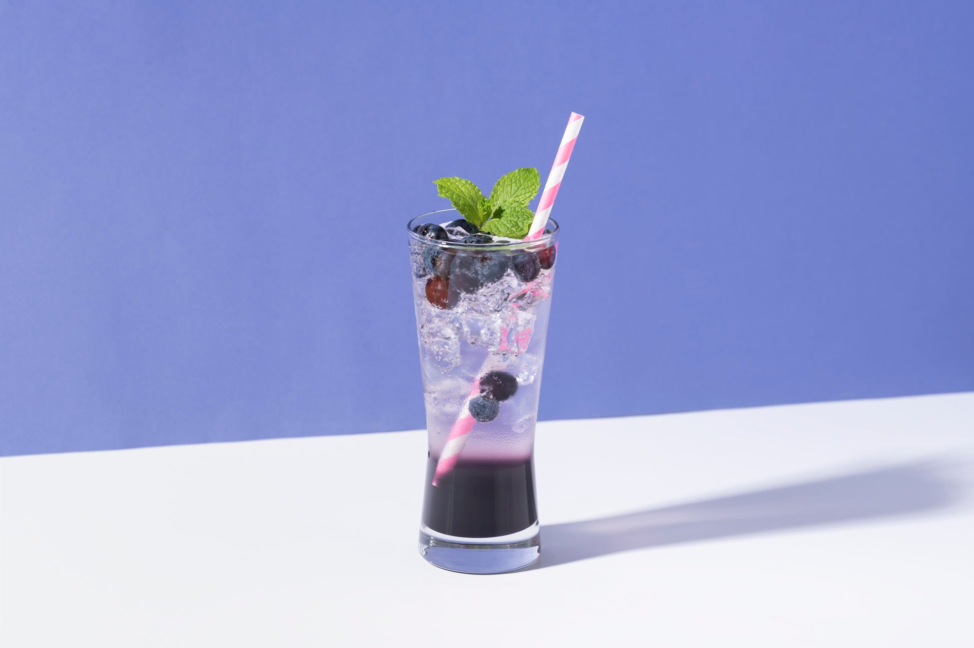 Blueberry lavender cold drink punch with ice on purple background